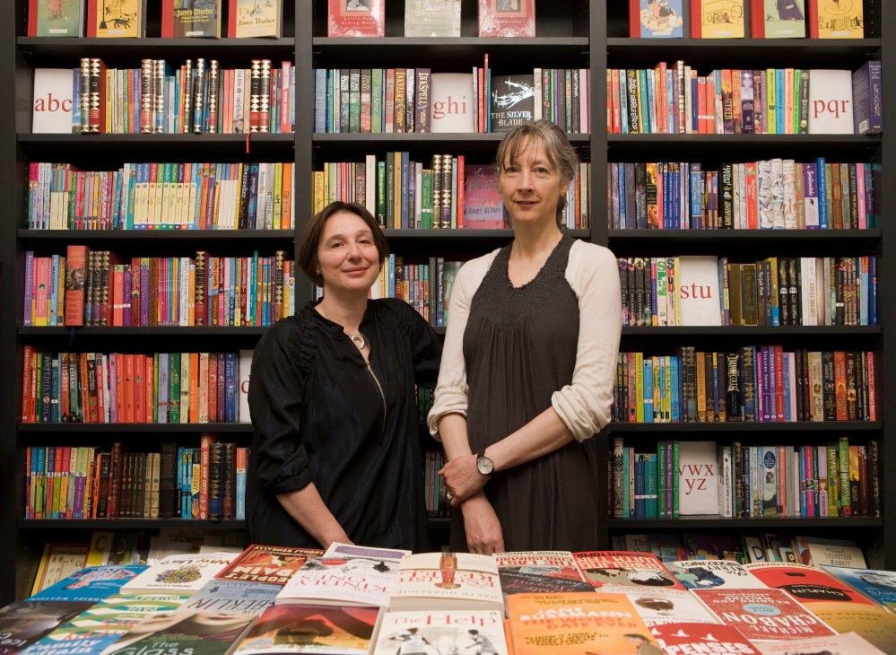 Felicity Rubinstein and Sarah Lutyens stand in front of shelves of books at their Lutyens & Rubinstein bookshop.
