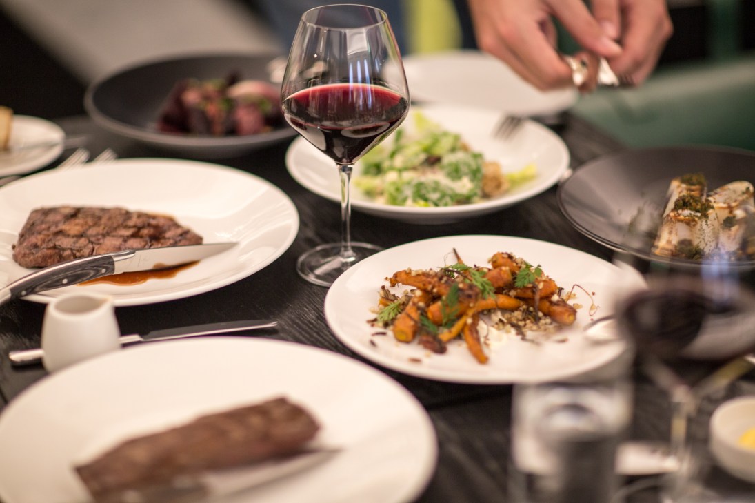 Fine dining table setting with red wine and plated dishes at The Cut restaurant.