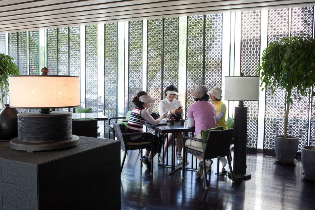 Members gathered in a modern café with geometric patterned screens at the Ananti golf club.