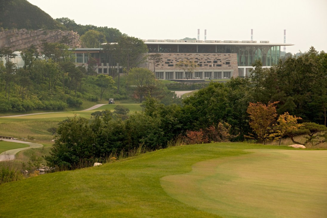 Haesley Nine Bridges Golf Clubhouse with modern architecture nestled in a forested mountain landscape.