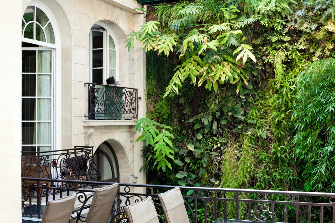 Pershing Hall's vertical garden with lush green foliage covering the facade beside classical stone architecture and wrought-iron balconies.