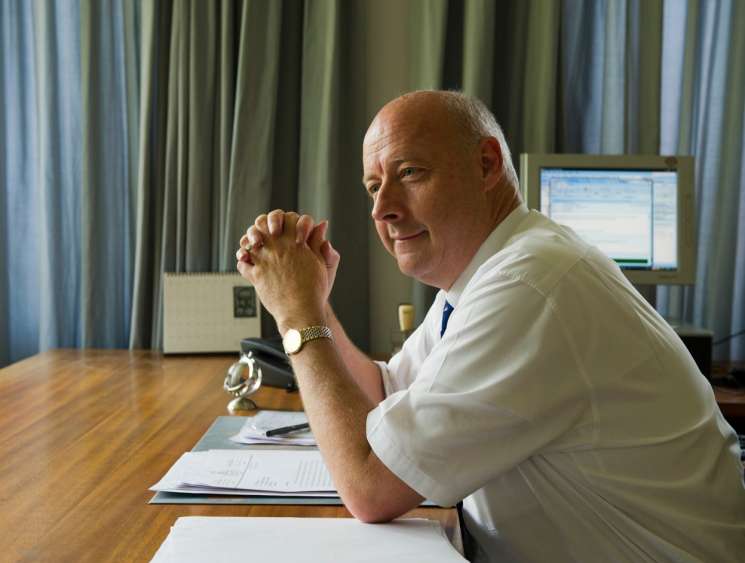 Danish ambassador Freddy Svane seated at his desk in New Delhi office, smiling at camera with clasped hands.