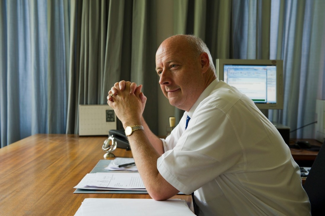 Danish ambassador Freddy Svane seated at his desk in New Delhi office, smiling at camera with clasped hands.
