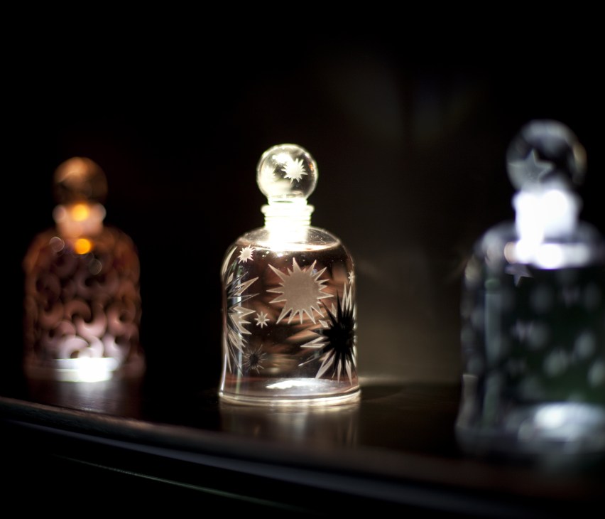 Serge Lutens perfume bottle with etched sun design and stopper on display.