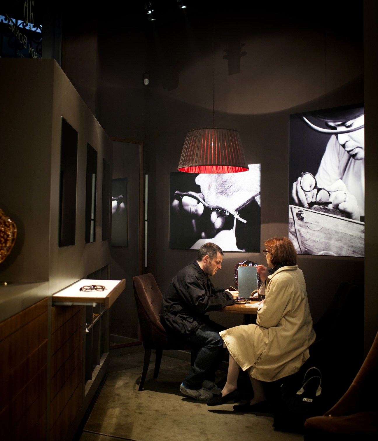 Franck Bonnet of Maison Bonnet sits at a table with a customer inside the spectacle shop's intimate retail space.
