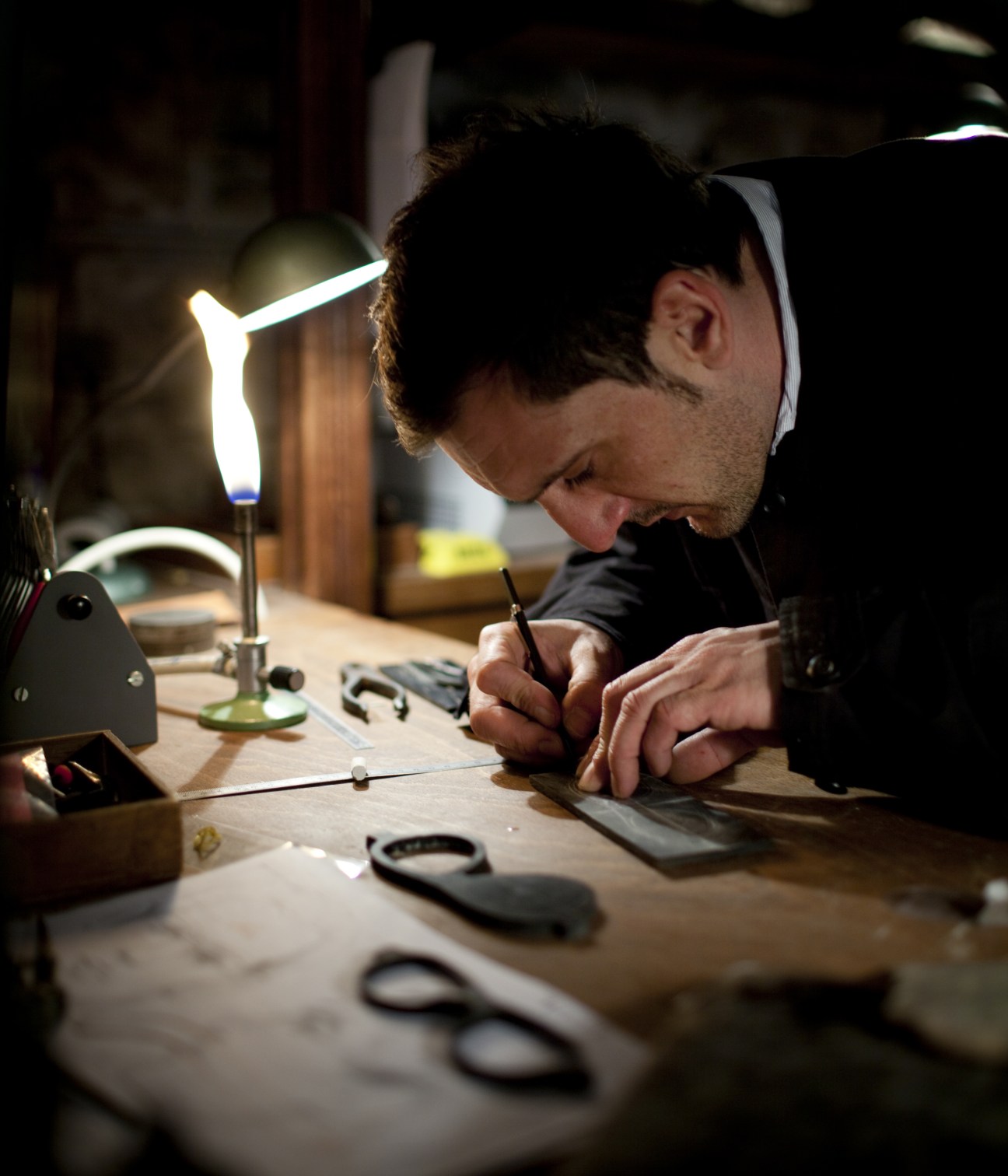 Craftsman working at Maison Bonnet atelier, hand-assembling spectacles under bright work lights.