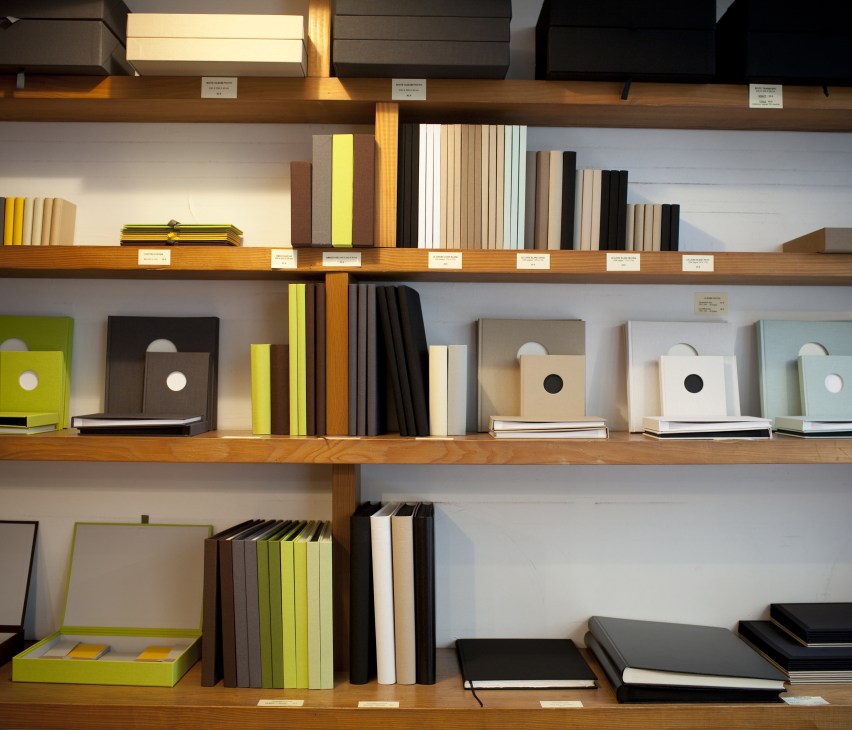 Wooden shelves displaying organized paper goods and notebooks in various colors at Papier Plus.
