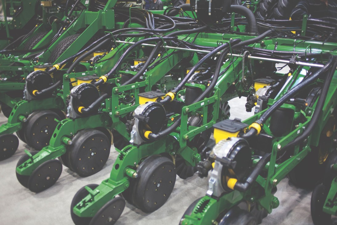 John Deere automatic seed planters with green frames and yellow components displayed at the farm machinery show.