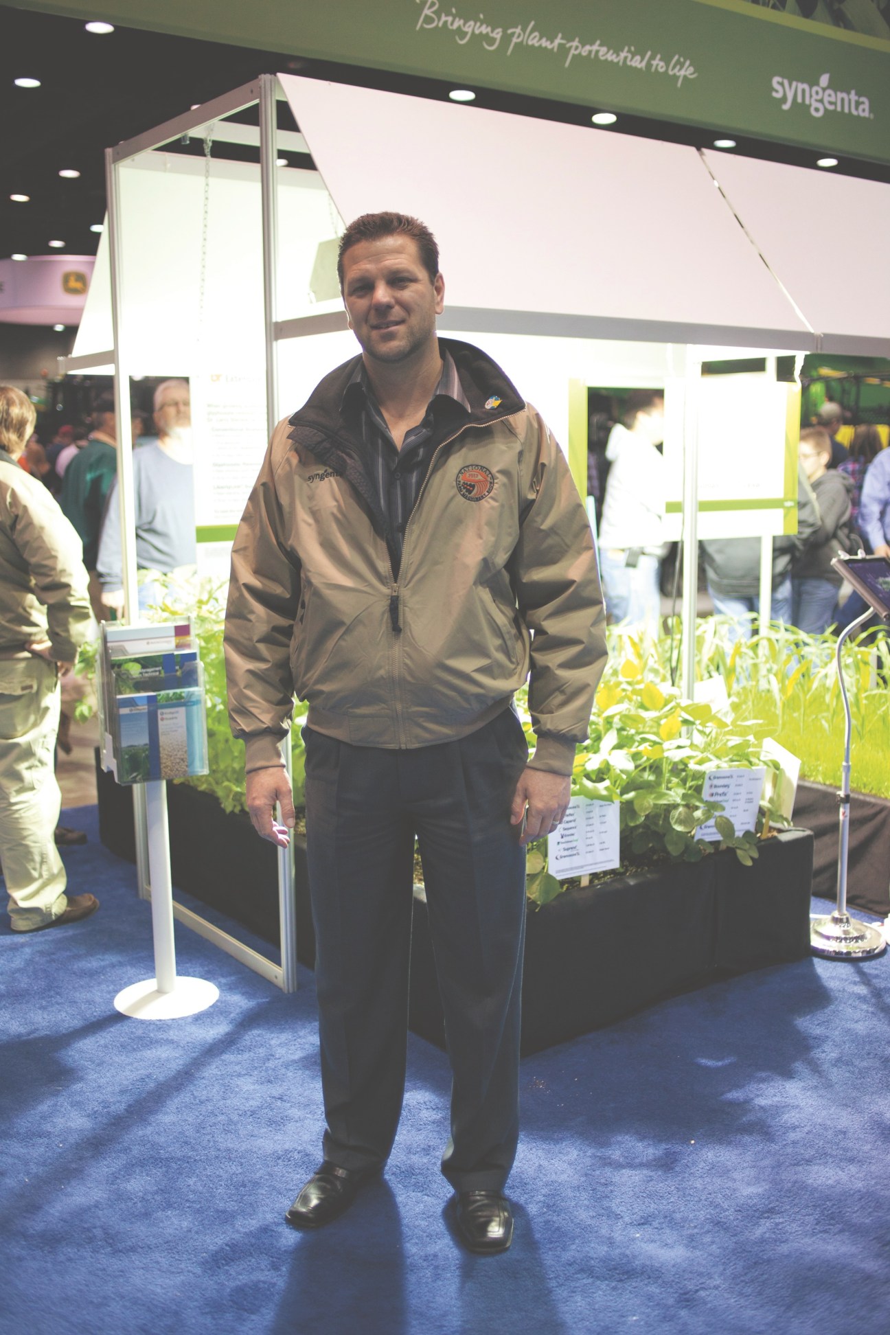 Steve Pigg of Syngenta standing at the National Farm Machinery Show booth with plant displays.