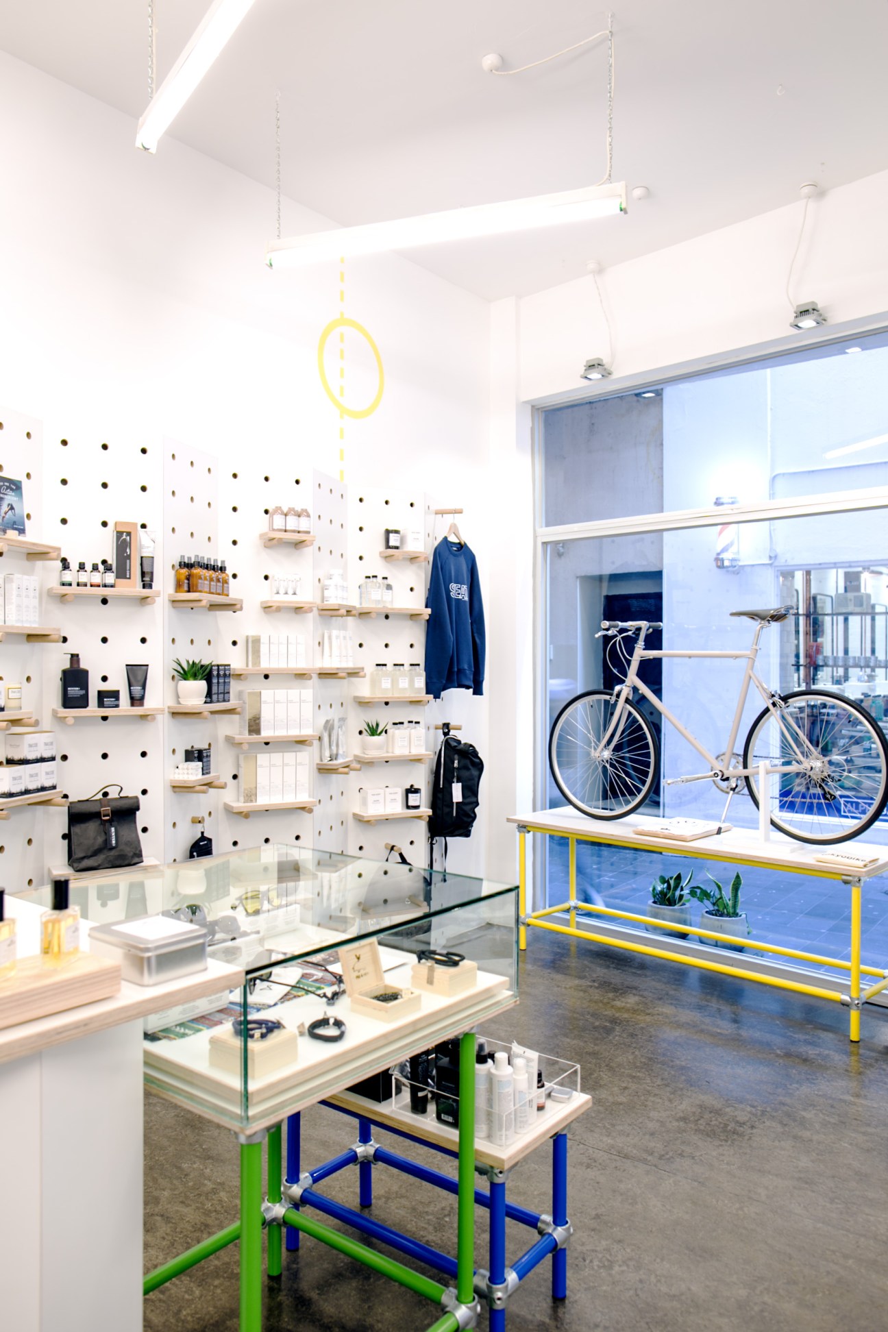 Interior of The Practical Man sportswear shop in Melbourne showing pegboard wall display, wooden shelving, bicycle in window, and colorful display table.
