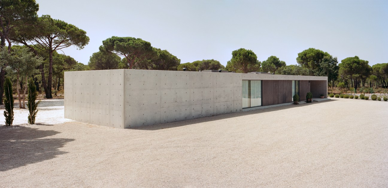 Modern concrete house with glass windows set among pine trees in Comporta, Portugal.
