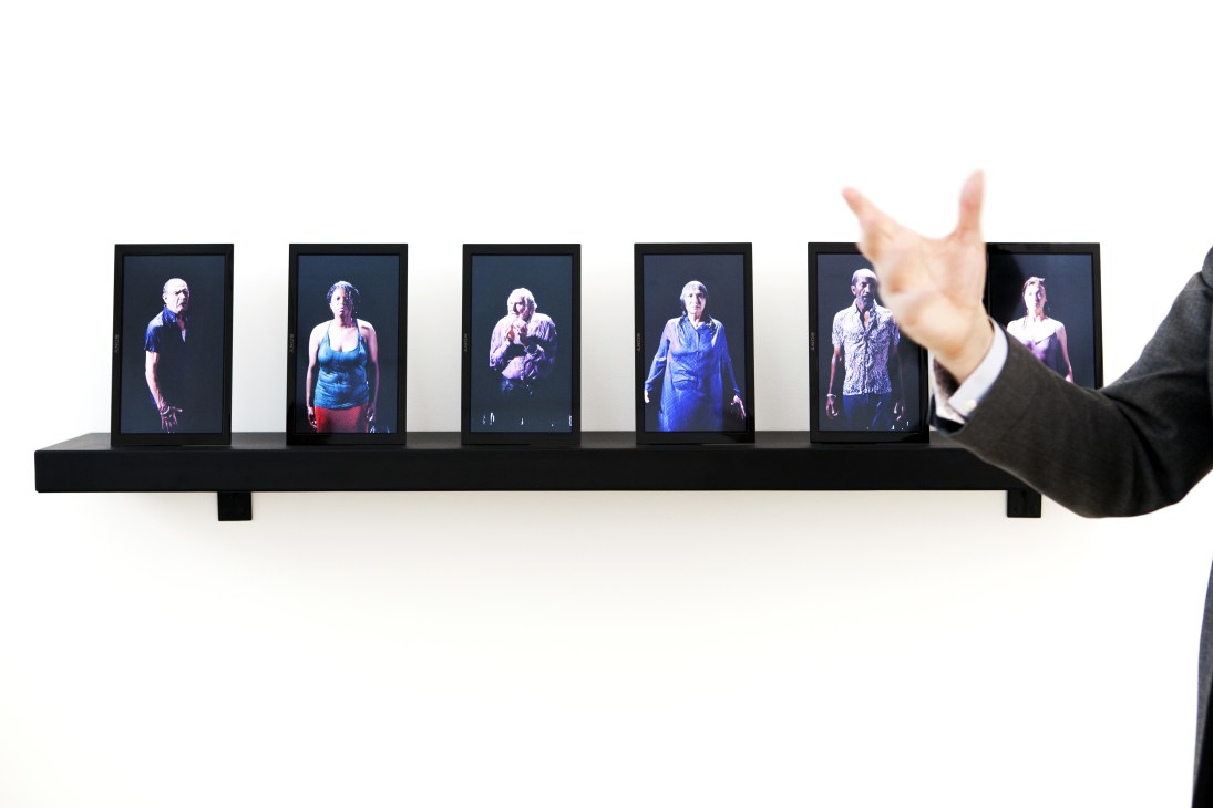 'Small Saints' by Bill Viola, a video art installation displaying portrait figures on illuminated screens mounted on a black shelf.