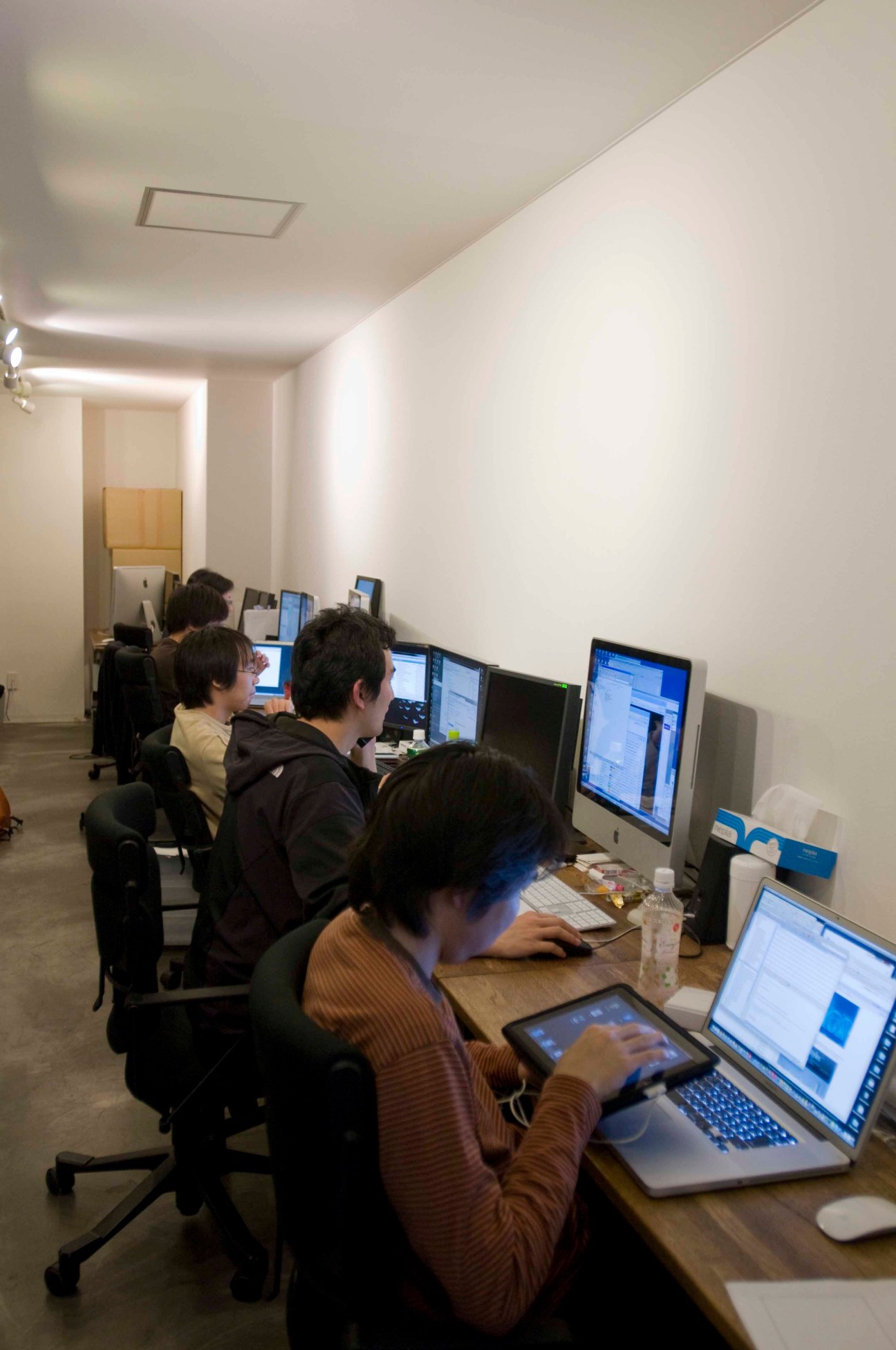 Web designers working at computers in a minimalist office space near Shibuya station in Tokyo.