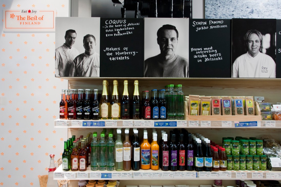 Best in Finland shop display with shelves of Finnish food products, beverages and black and white portraits of producers above.