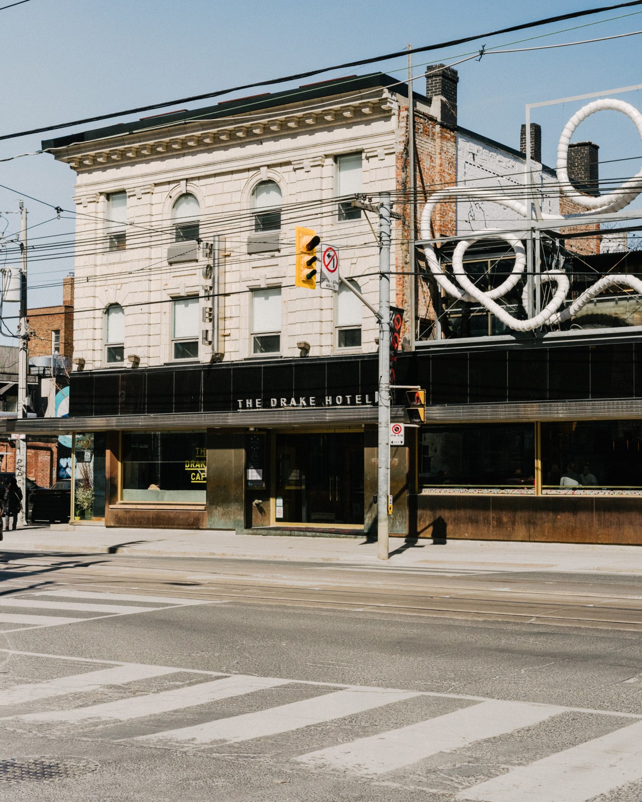 The Drake Hotel exterior on Queen West in Toronto, featuring historic architecture with street-level storefront and artistic signage.