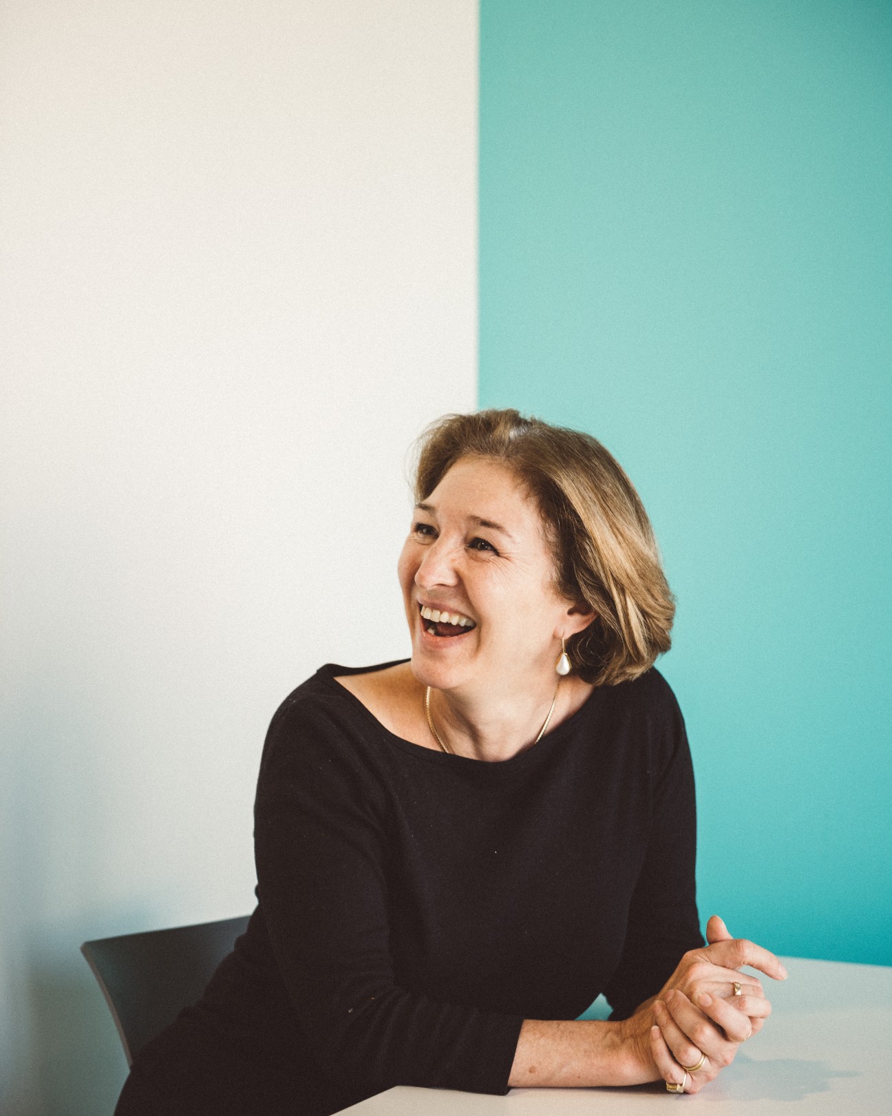 Anne-Marie Slaughter, president and CEO of New America, smiles while seated against a turquoise and white background.
