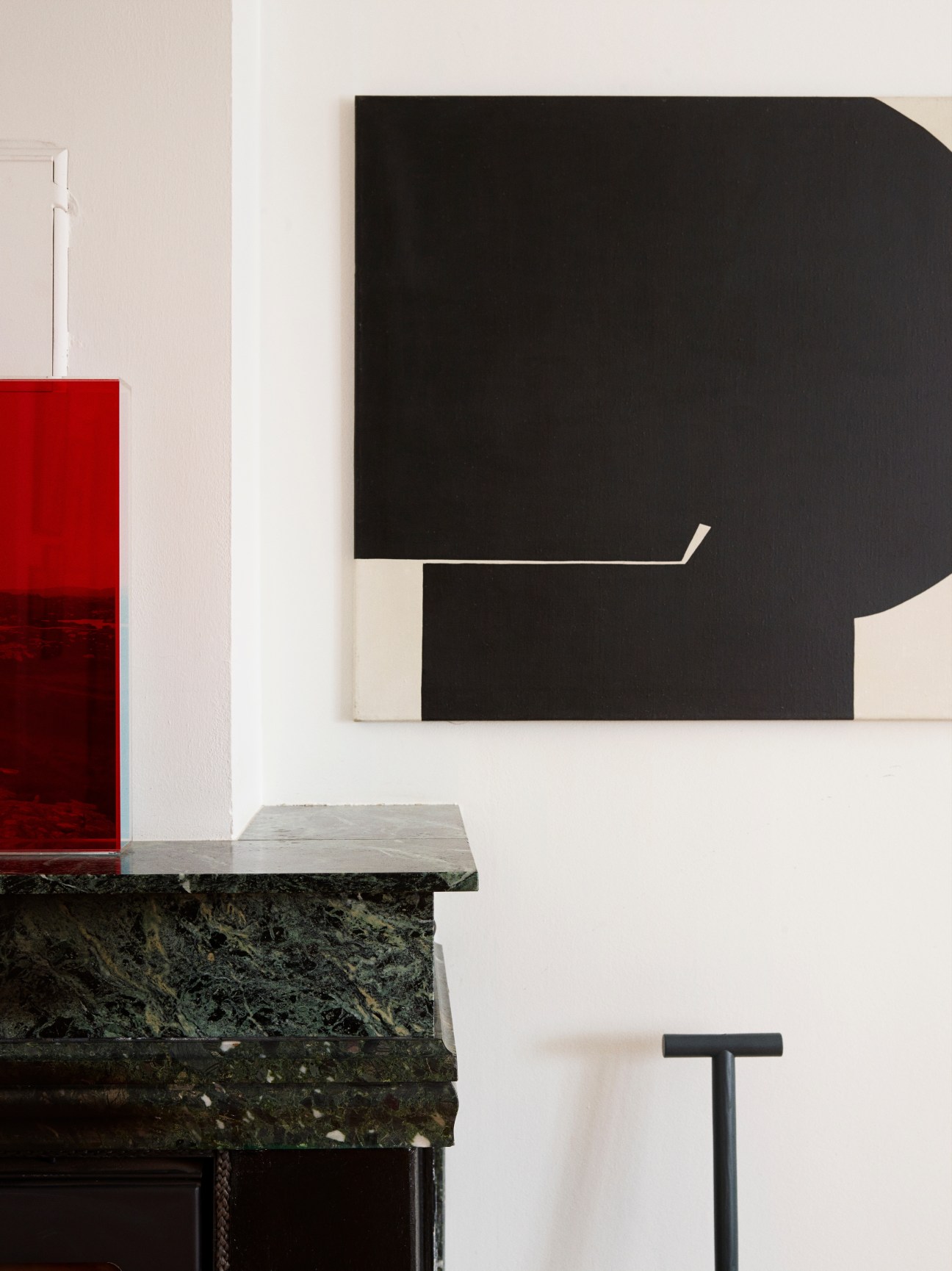 Red perspex artwork by Ebbe Stub Wittrup and black abstract painting by Kai Führer on white wall above marble table.