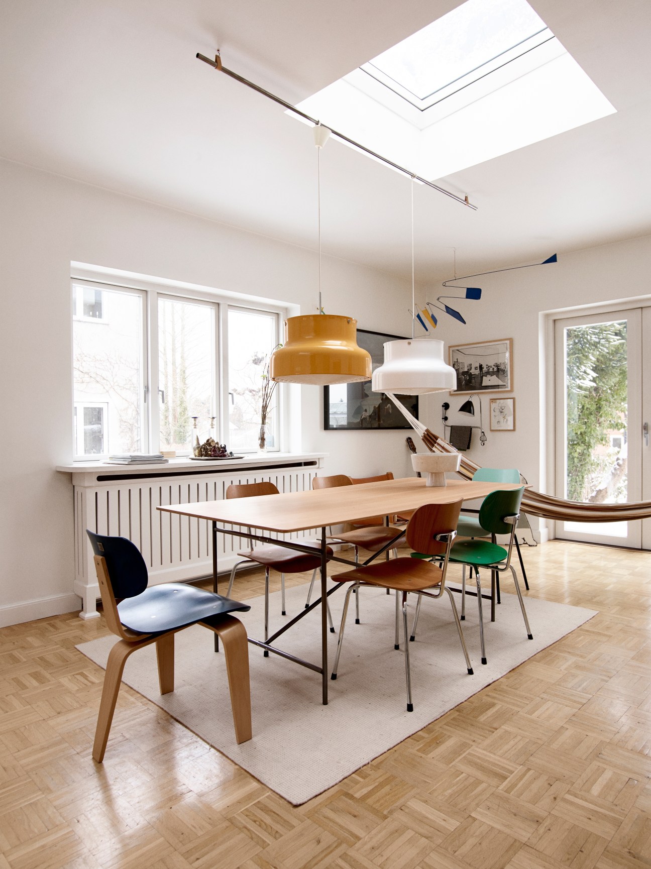 Dining room with Egon Eiermann table and chairs by Please Wait To Be Seated, pendant lights, and skylight.