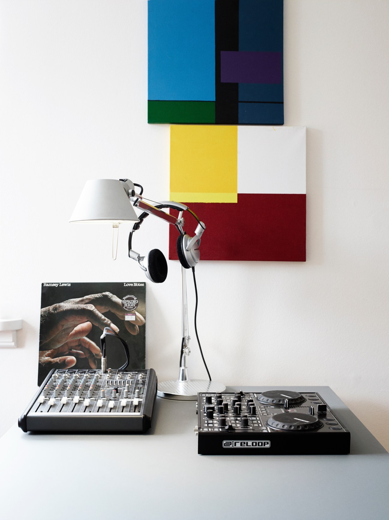 Music production setup with mixing desk, headphones, desk lamp and vinyl record in Thomas Ibsen's home.