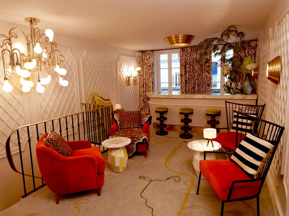 Hotel Thoumieux lounge with red velvet seating, brass chandelier, and patterned wallpaper.