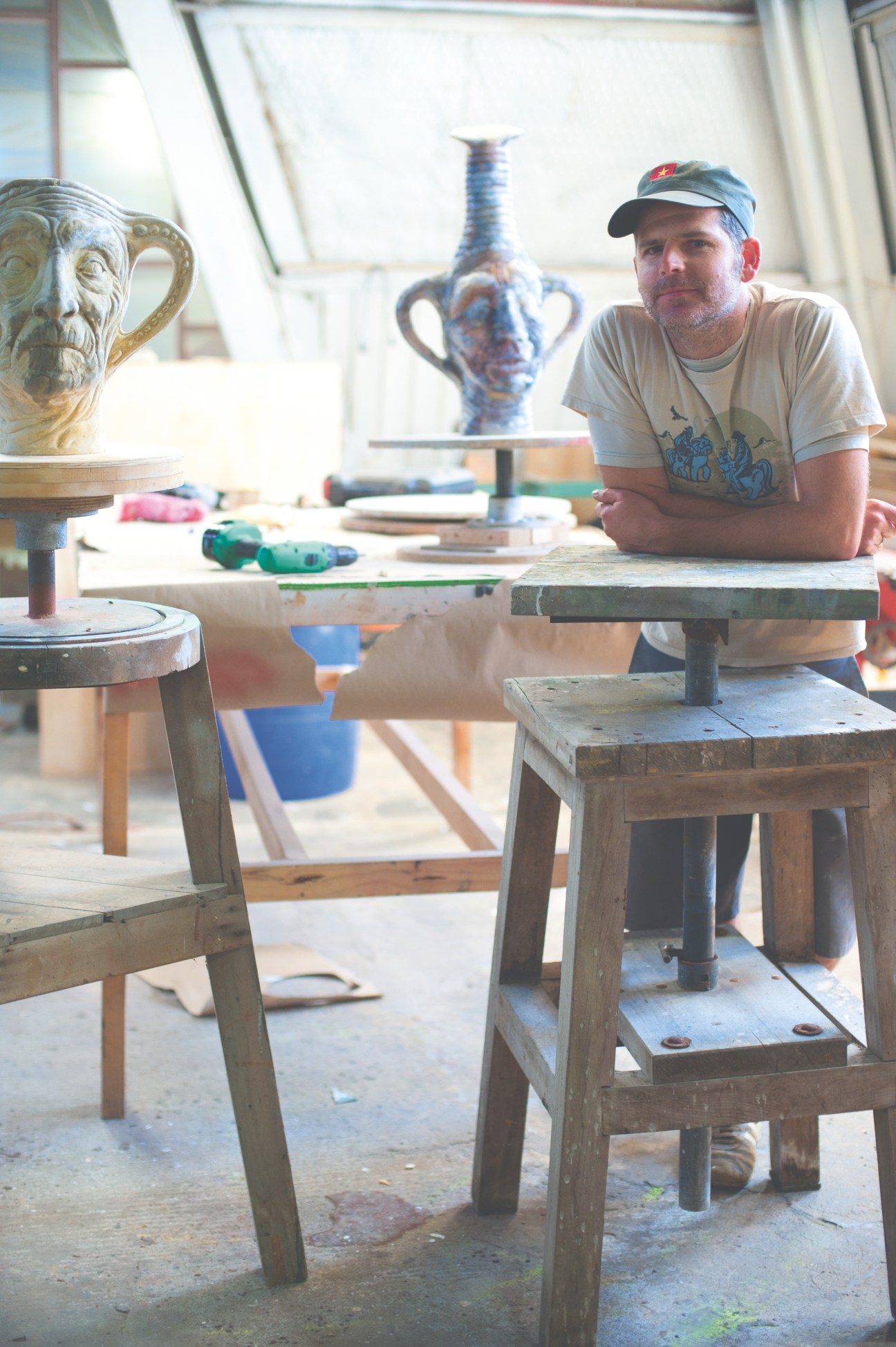 Jake Yocum, Izzat Design co-director, in a creative workshop surrounded by sculptural props and design materials.