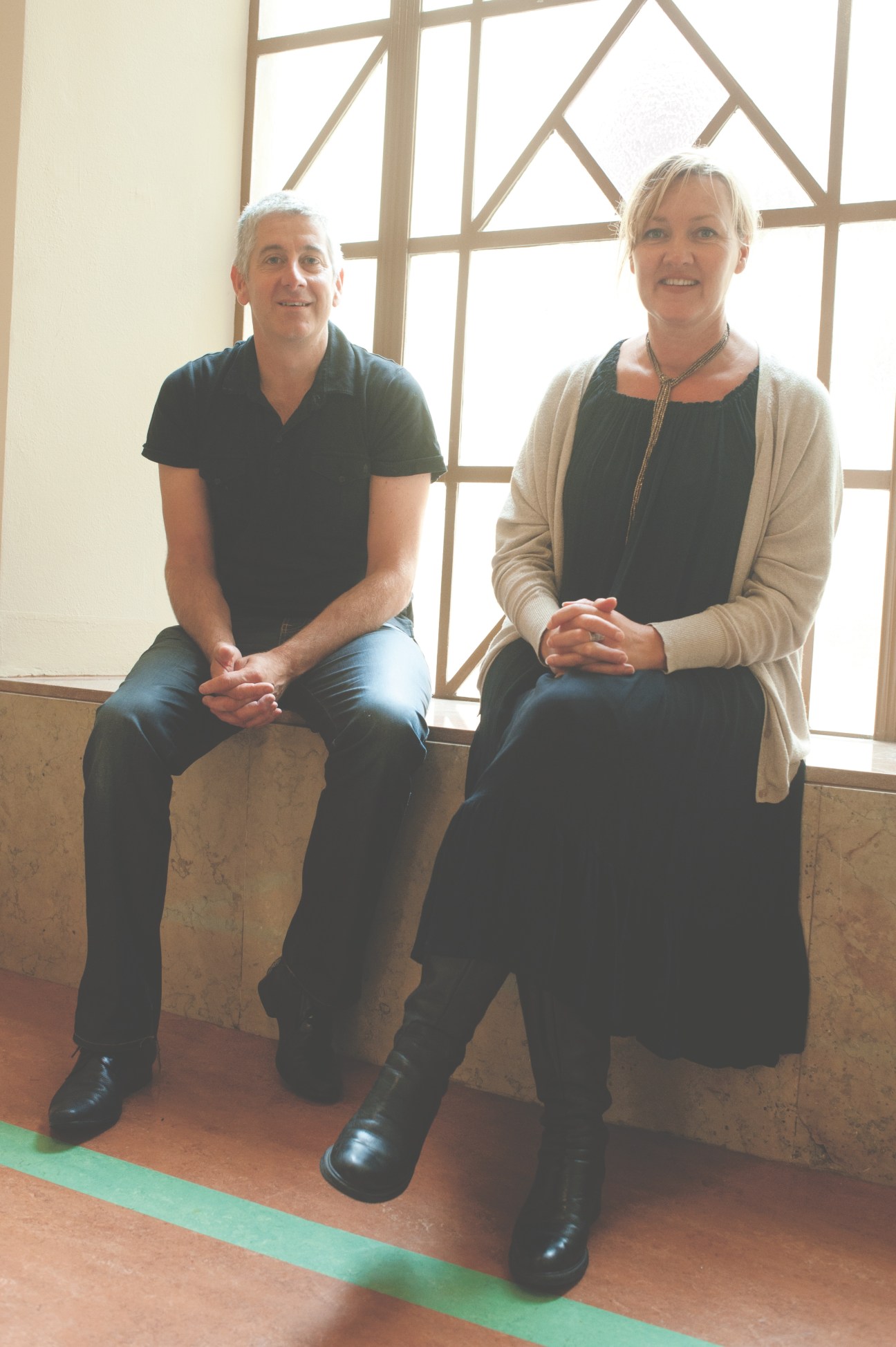 Two people sitting by a large geometric window at The Formary