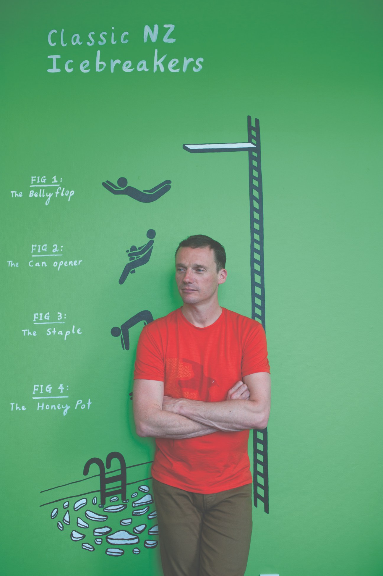 Rob Achten, Icebreaker creative director, stands against a green wall with illustrated Icebreaker product exercises labeled as classic NZ Icebreakers.