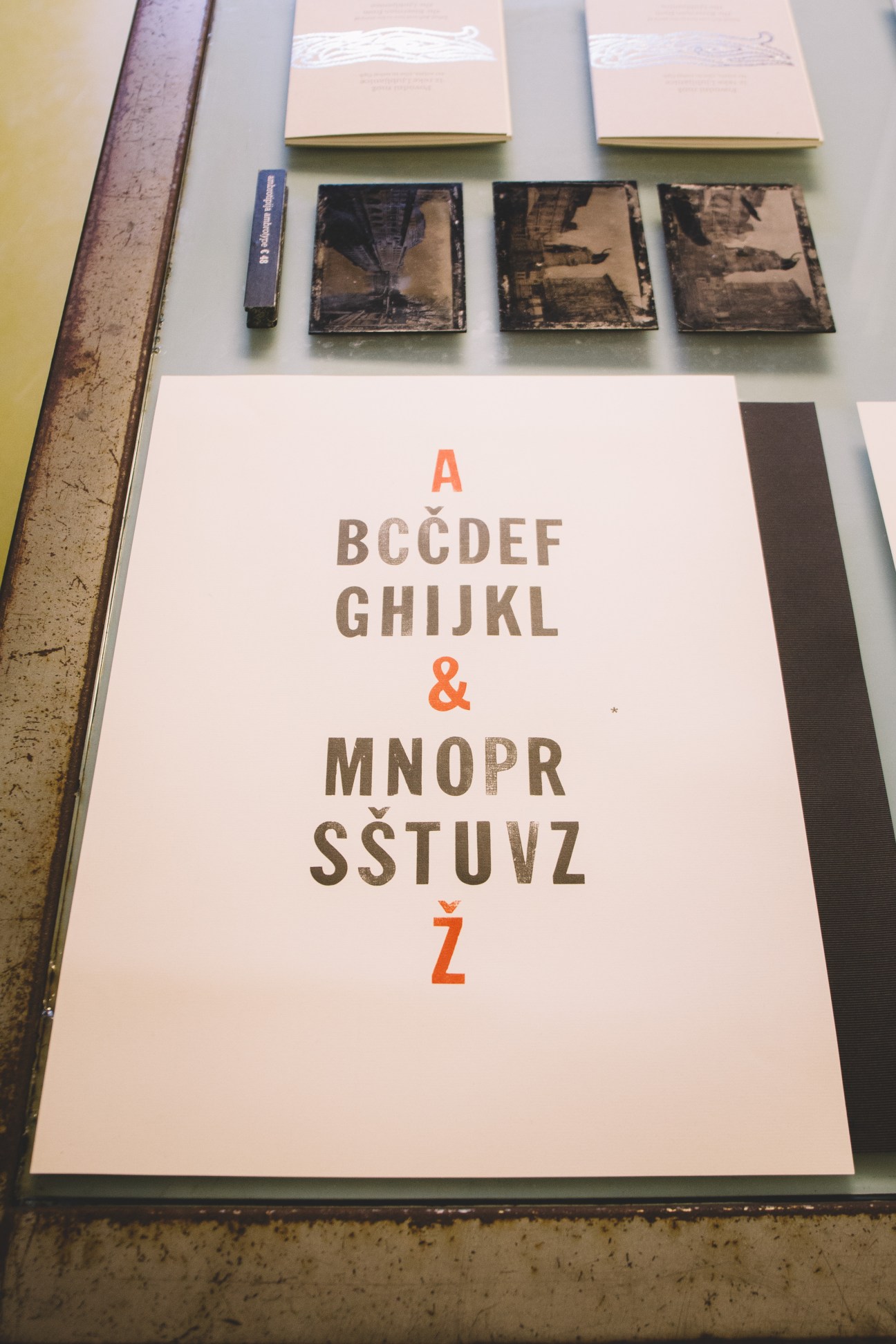 Letterpress typography display at TipoRenesansa showing an alphabet design with orange and brown characters on white paper, with vintage printing materials displayed above