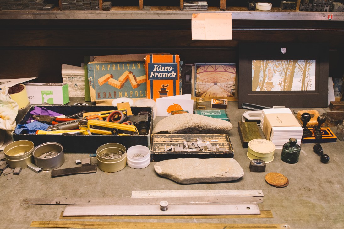 Vintage printing equipment and materials displayed at TipoRenesansa letterpress studio, including metal tins, tools, and historical printed items.
