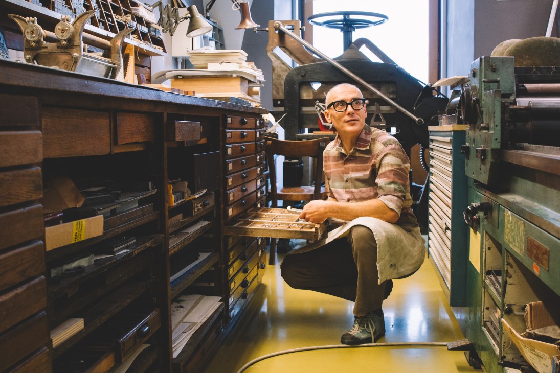 Marko Drpic sits among historic printing equipment at TipoRenesansa letterpress studio in Ljubljana.