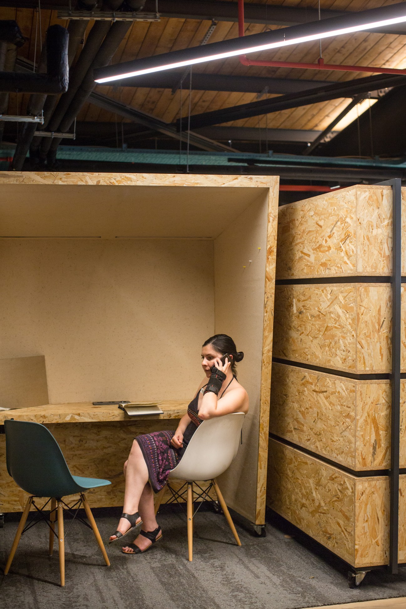 Woman on phone in a private OSB-walled office nook at Atolye co-working space