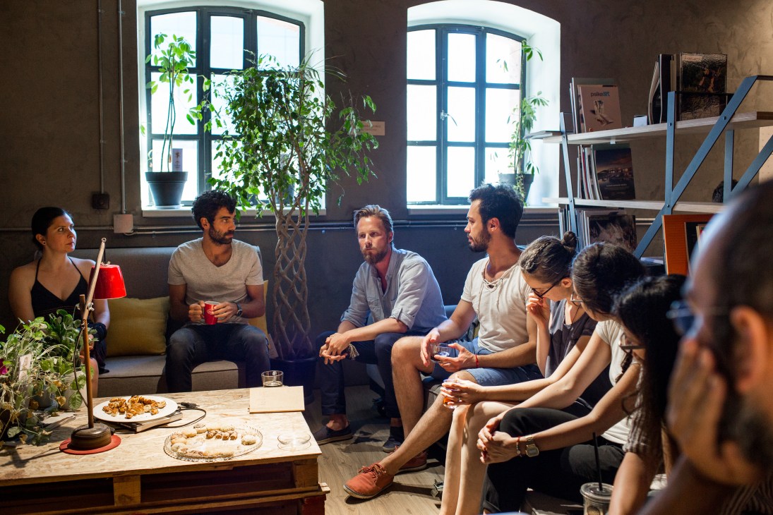 Group of diverse professionals sitting in a lounge area during a daily feedback session at Atolye co-working space.