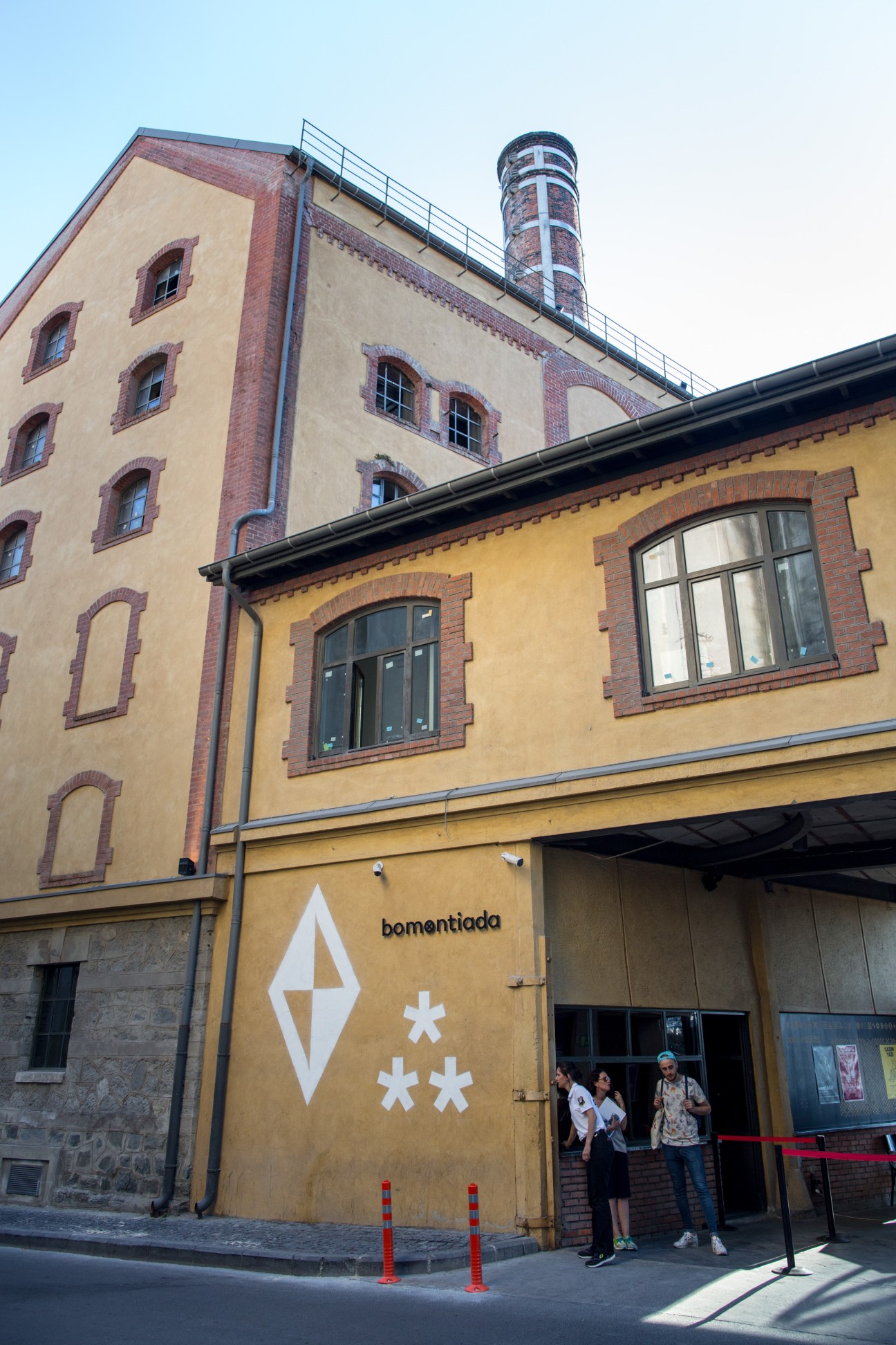Exterior of Atolye co-working space housed in a restored Ottoman-era brewery building with yellow facade and brick details.