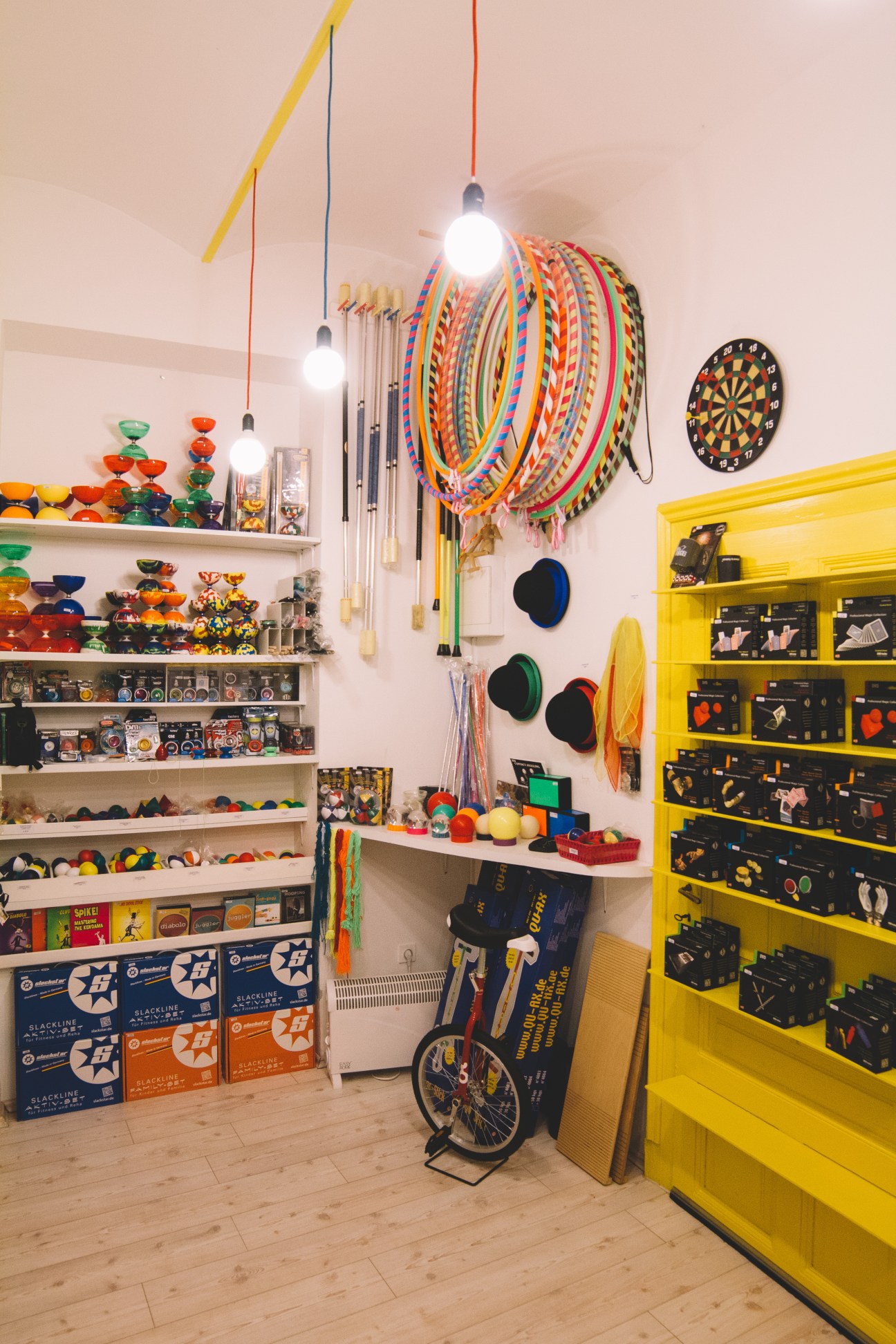 Colorful toy shop interior with shelves of toys, yellow storage units, hanging games, and pendant lights at Tojeto.