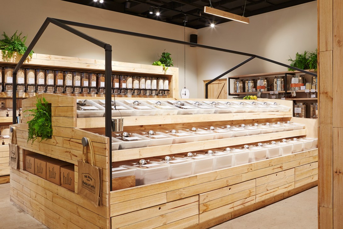 The Farm Wholefoods café counter displaying pantry items in glass dispensers with wooden design.