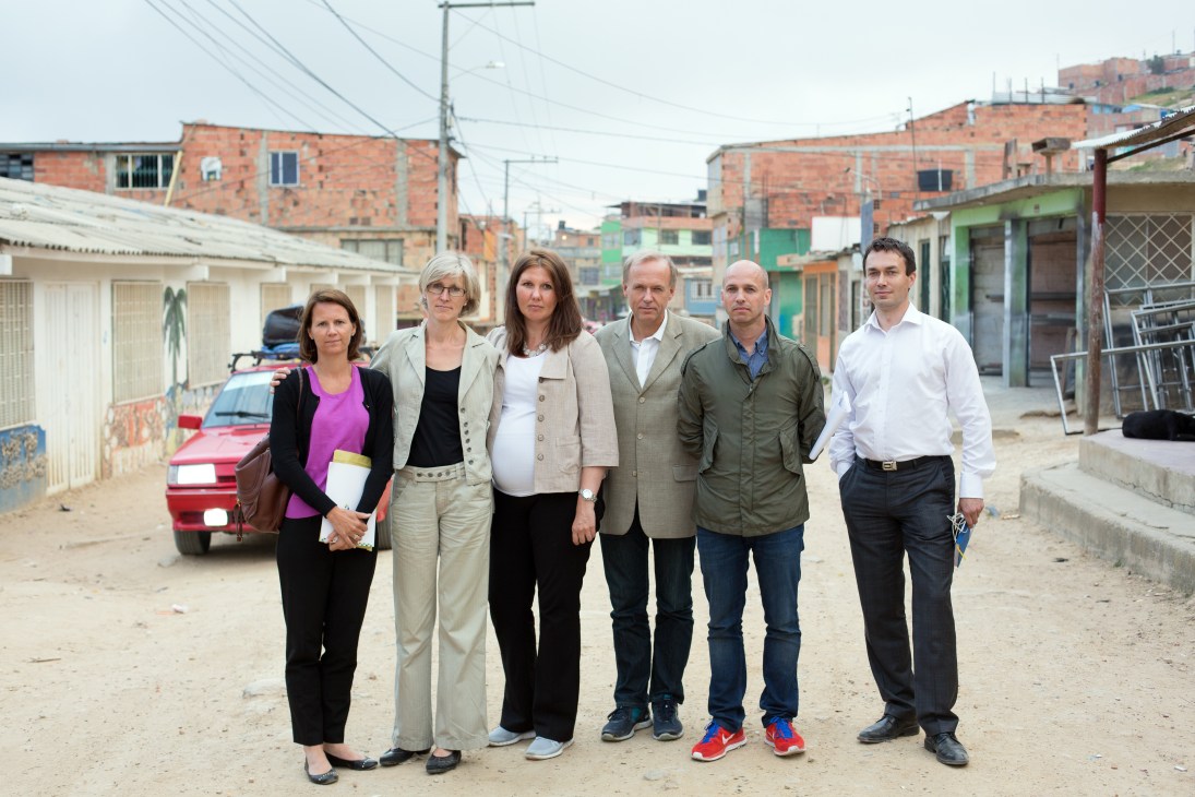 Norwegian diplomatic team stands in a street in Soacha, Colombia, lined with basic brick houses.