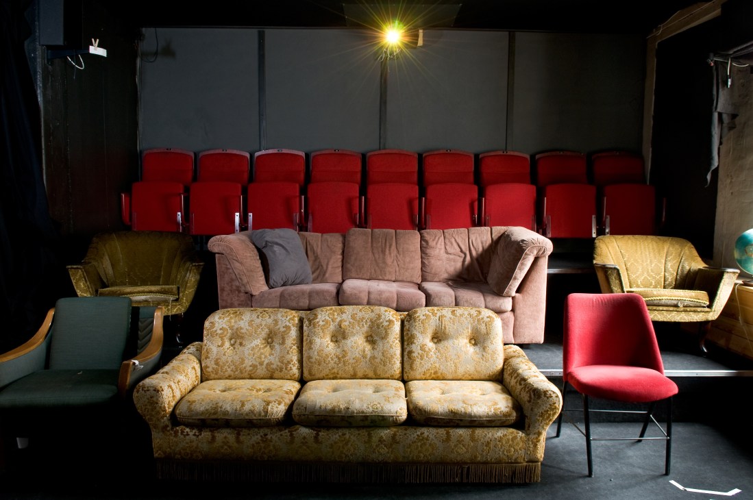 Screening room at Plymserafin with vintage sofas facing red cinema seats and a projection screen.