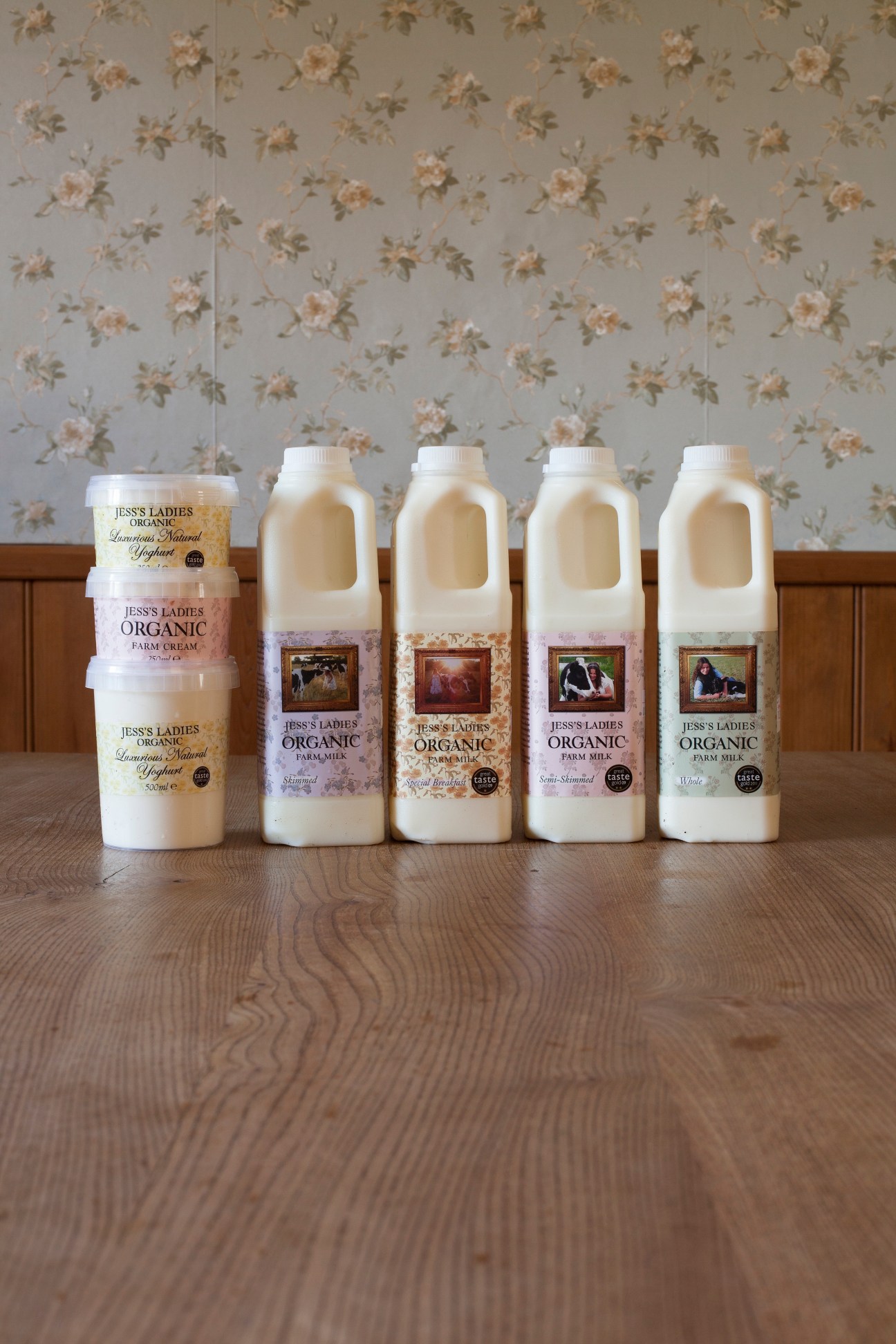 Jess's Ladies Organic Farm Milk products displayed in bottles and containers on a wooden table.