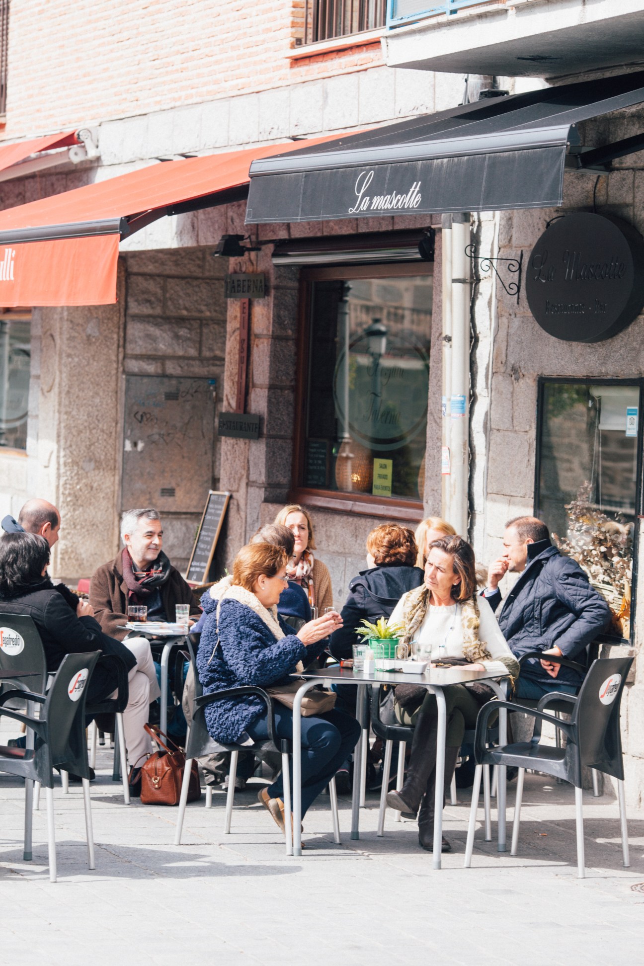 People seated at outdoor tables of La mozzarella café in Torrelodones, Spain.