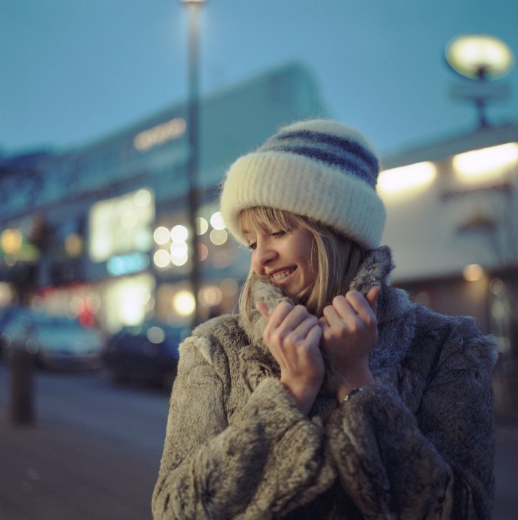 Hairdresser Tota Johannesdottir smiling in winter clothing on a Reykjavik street at dusk.