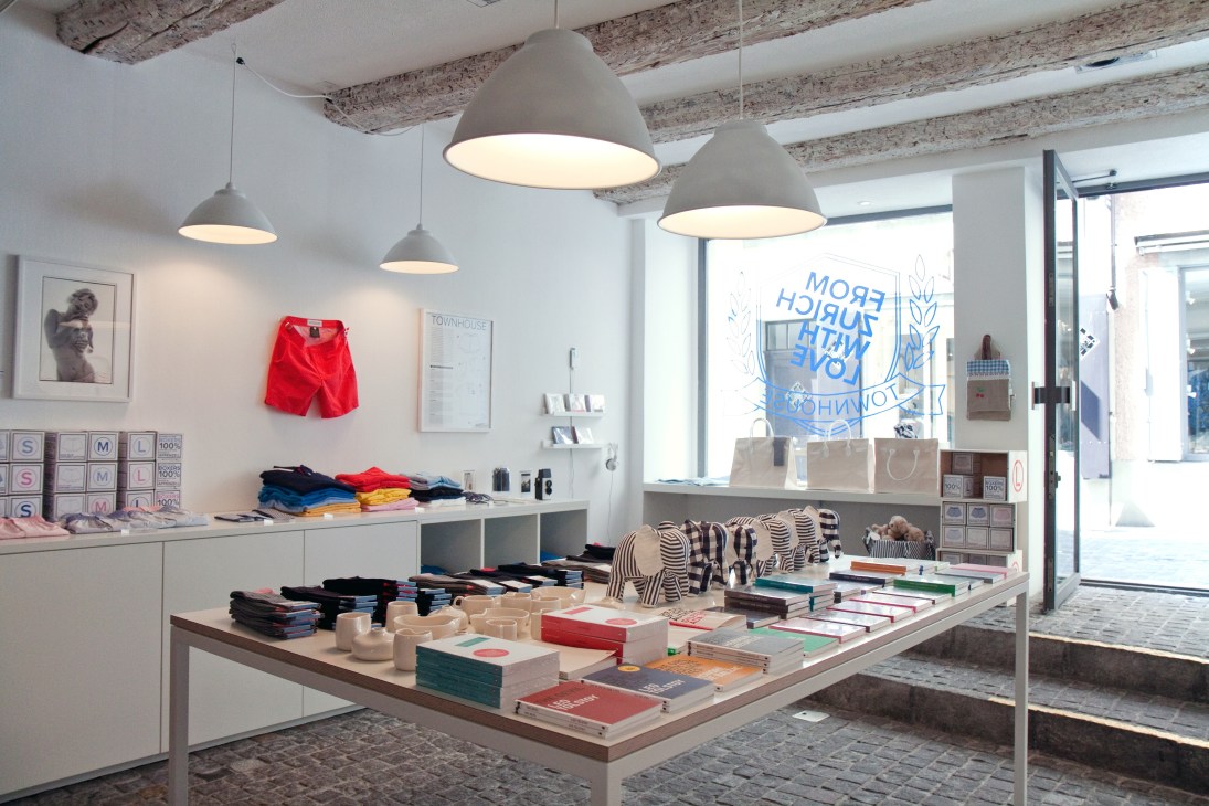 Interior of Townhouse retail shop in Zürich with curated products on display tables and shelves under pendant lights.