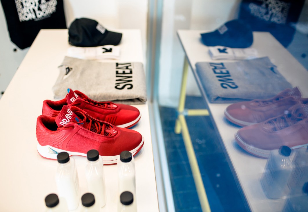 Red trainers and branded apparel displayed on white shelving at The Practical Man sportswear shop.