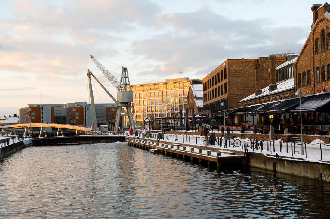 Trondheim waterfront with brick buildings, a yellow bridge, and snow-covered dock area along the canal.