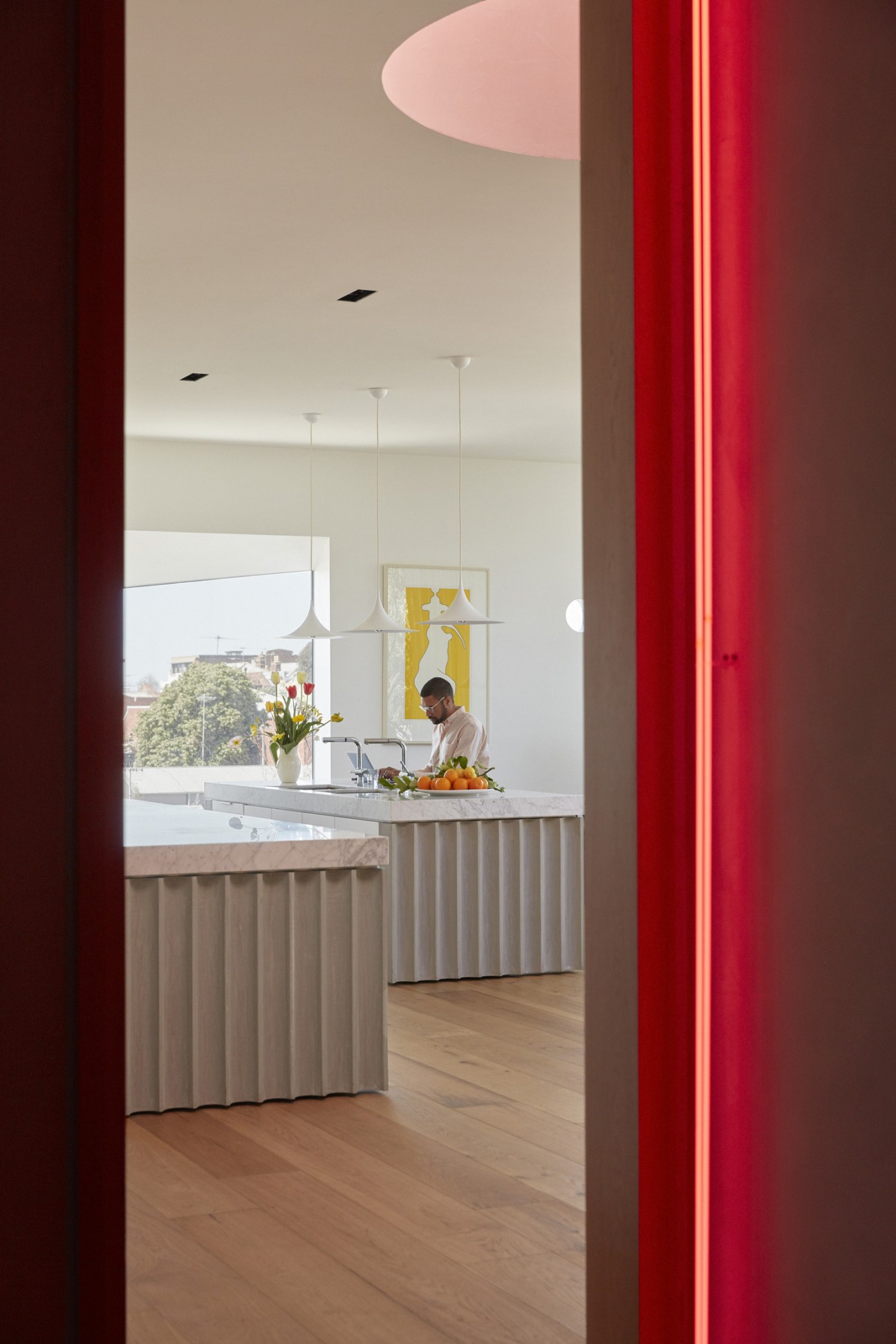 Modern kitchen with fluted marble countertop, pendant lights, and large windows overlooking Melbourne's cityscape and eucalyptus trees.