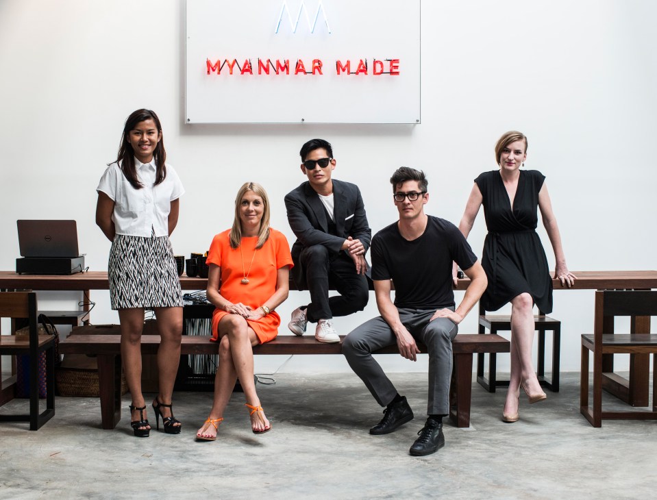 Five members of the TS1 team pose in front of a neon sign reading 'Myanmar Made' in a white minimalist interior space.
