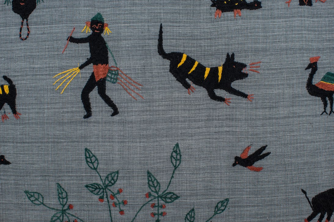 Hand-woven textile with embroidered black animals and colorful details on gray fabric.