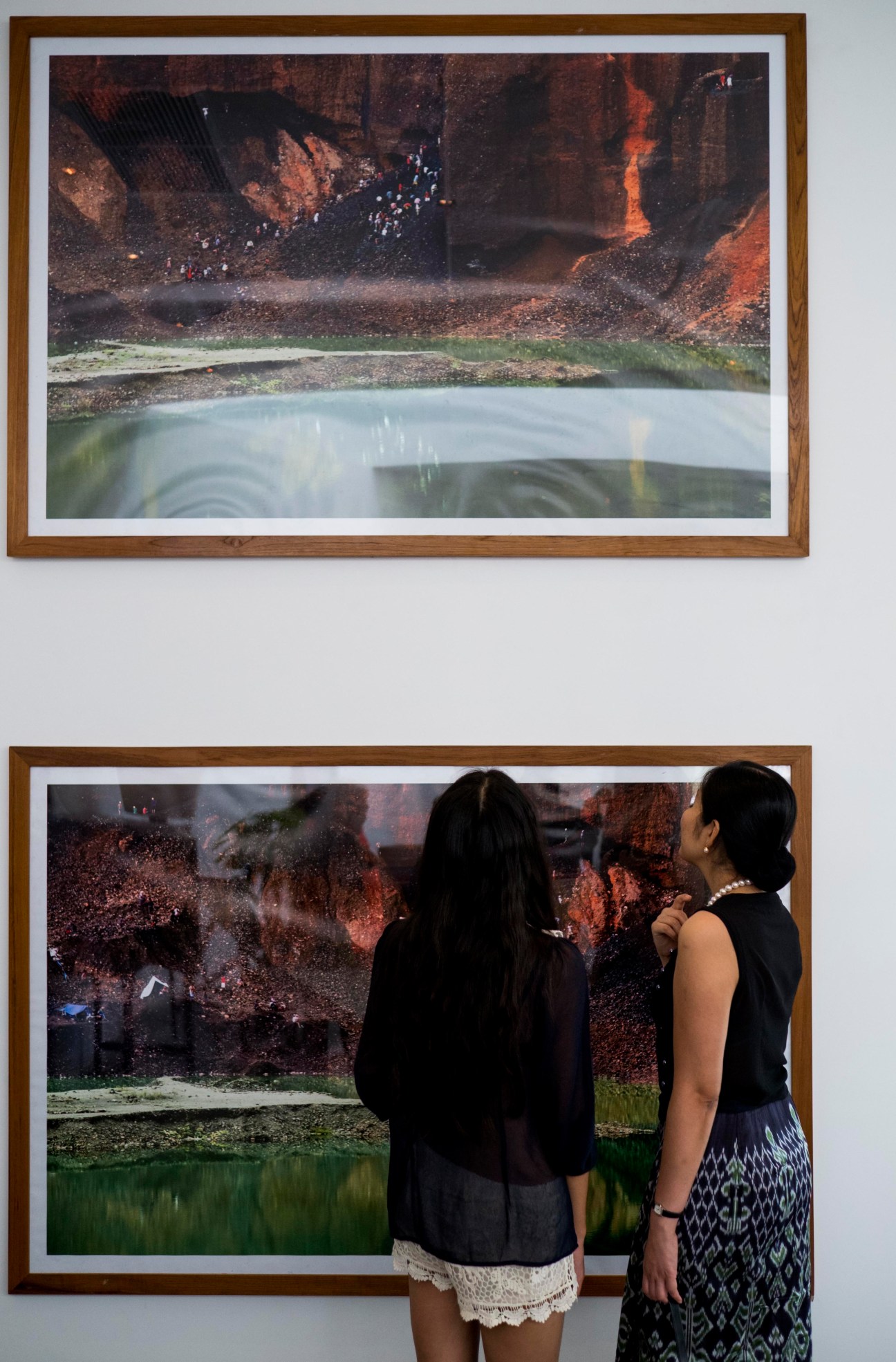 Two women viewing framed photographs of landscapes displayed on a white wall at TS1 gallery.