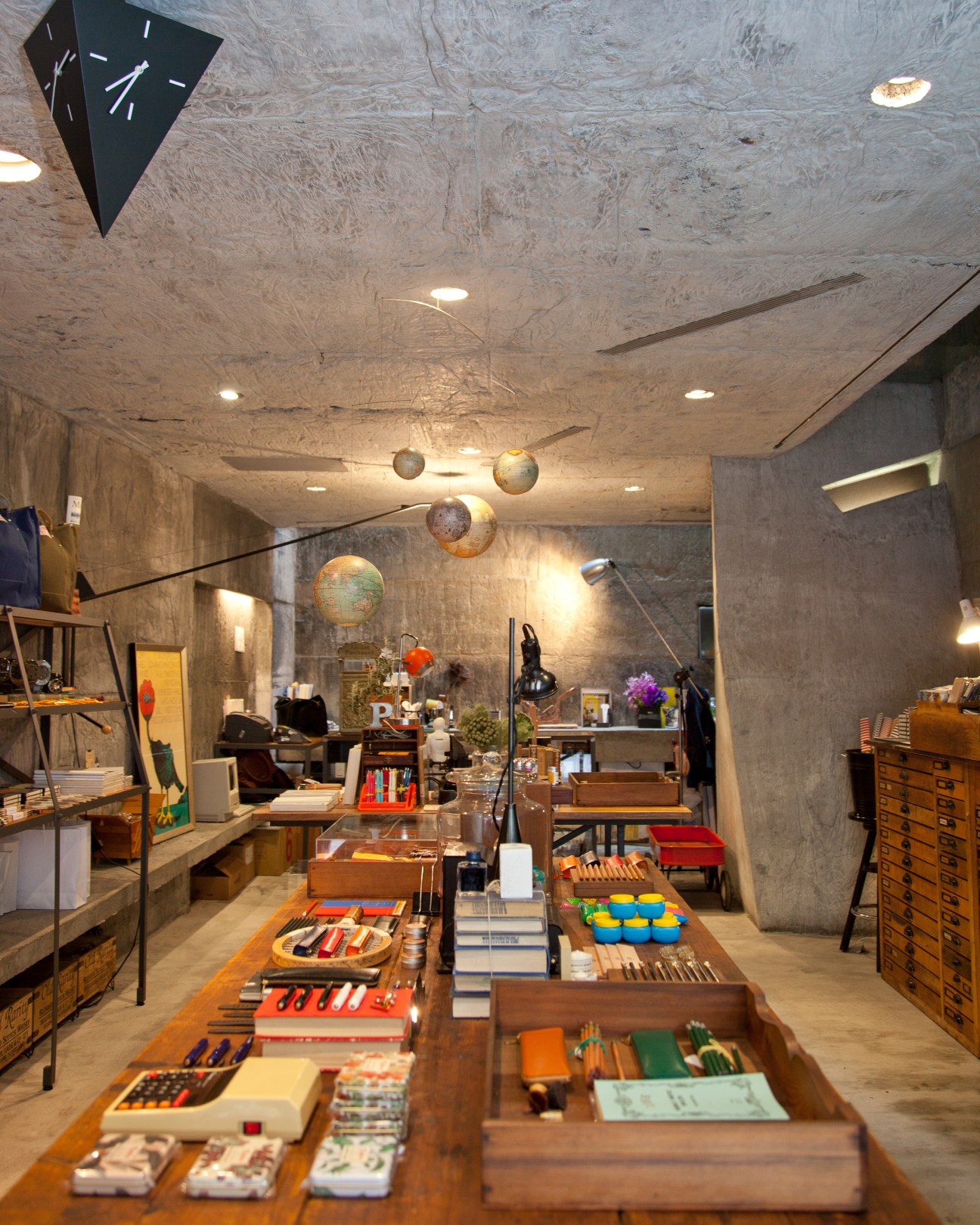 Interior of Tools to Live By stationery shop showing wooden display tables with art supplies and globes hanging from ceiling.