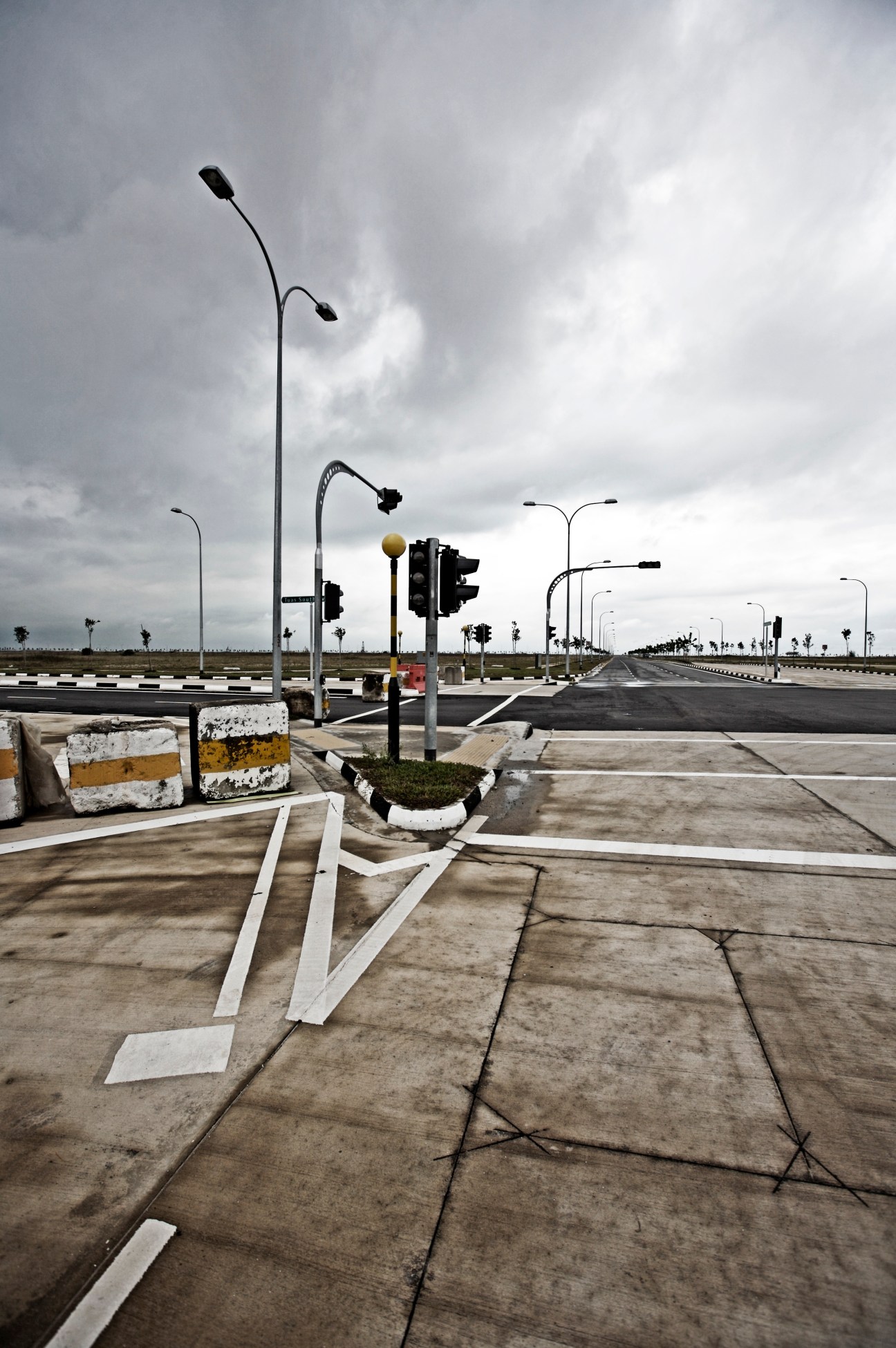 Empty highway with street lights and traffic signals under cloudy sky in Singapore's Tuas industrial zone