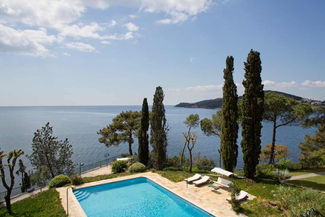Swimming pool overlooking the Sea of Marmara with cypress trees and lounge chairs on the Riza Dervis house terrace.